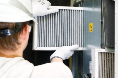 Hvac filtresi ev merkezi havalandırma sistemini değiştiriyor. Askerler fırında filtre değiştiriyor. Döner ısı dönüştürücüdeki filtreyi değiştir.