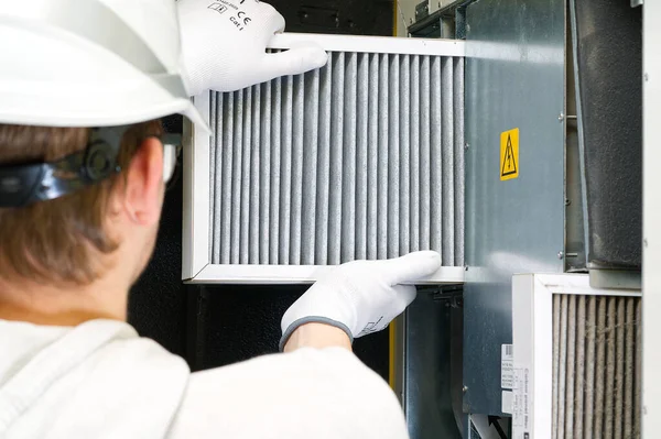 Hvac filtresi ev merkezi havalandırma sistemini değiştiriyor. Askerler fırında filtre değiştiriyor. Döner ısı dönüştürücüdeki filtreyi değiştir.