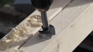 Tahtadaki deliği öğütmek. Fabrika işçisi iş başında. Kontra-lavabo matkabı deliğe batırır. İnsan ahşap tahtada delik açmak için sondaj makinesi kullanır.