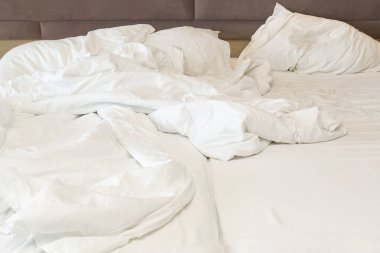 Fırtınalı bir aşk gecesinden sonra kırışık yatak. Sevgililer Günü için yatak odasındaki yumuşak beyaz ve buruşuk battaniyeye yakın çekim.