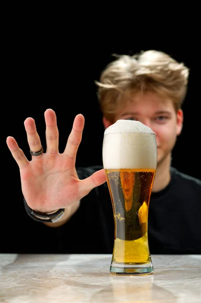 No alcohol. Young man refuses to drink beer. Stop drinking. Say no to alcohol . Black Background