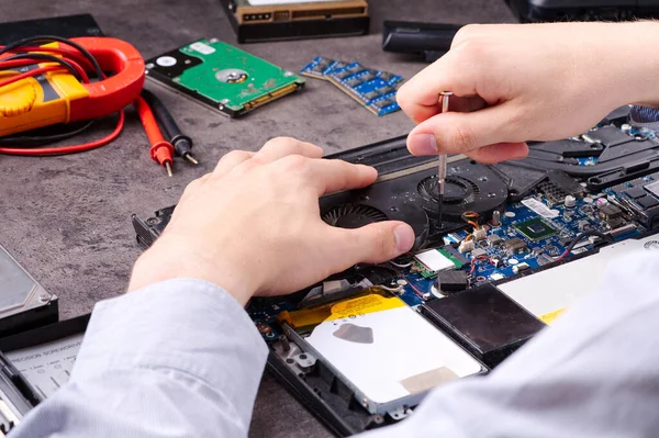 Hands fixing motherboard of pc or laptop notebook close up in service. Laptop repair service. PC hardware upgrade and maintenance. Engineer fixing broken notebook.