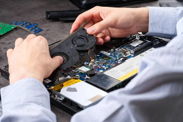Hands fixing motherboard of pc or laptop notebook close up in service. Laptop repair service. PC hardware upgrade and maintenance. Engineer fixing broken notebook.