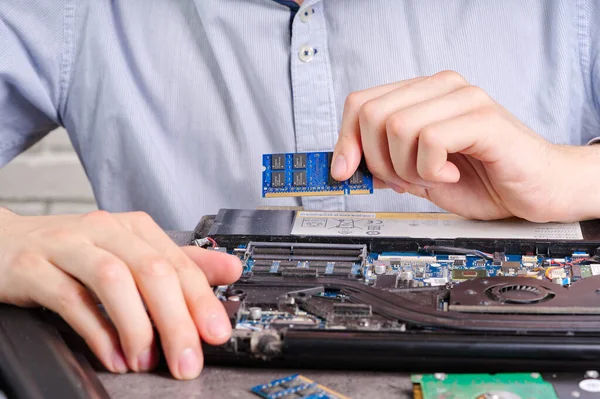 Notebook repair. Man disassembles a laptop. Removes the keyboard. Computer service and repair concept. Laptop disassembling in repair shop, close-up.