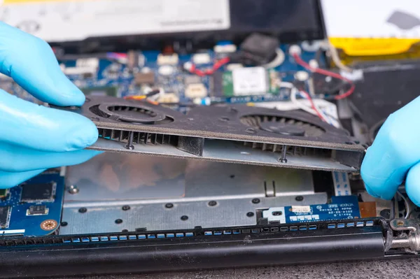 Hands of a technician repairing a broken laptop computer. Laptop repair service. Engineer fixing broken notebook. Computer technology. Laptop disassembling in repair shop, close-up.