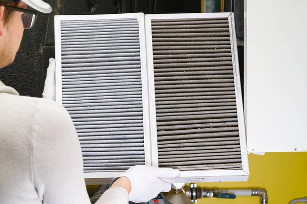 hvac filtresi değiştiriliyor. Merkezi havalandırma sistemindeki filtreyi değiştiriyorum, fırın. Ev merkezi klima sistemi için Kirli Hava filtresi değiştiriliyor. Döner ısı değiştiricideki filtreyi değiştir