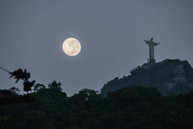 Rio de Janeiro, Brezilya 'da Kurtarıcı İsa ile dolunay - 19 Ocak 2022: Ay ve Kurtarıcı İsa' nın heykeli Rio de Janeiro 'daki Copacabana mahallesinden görüldü.
