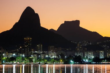 sunset at Rodrigo de Freitas Lagoon with Two Hill Brother and Gavea stone in the background in Rio de Janeiro, Brazil.