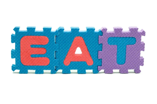 Word EAT formed with colorful foam puzzle mat isolated on white background — Stock Photo, Image