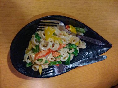 Siyah kasede servis edilen kaşık şeklinde kalamar makarnası.