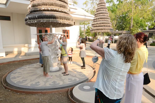 CHIANGRAI, THAILAND - MAR 2: Viajantes não identificados visitam Wat Rong Khun um famoso templo branco no norte da Tailândia em 2 de março de 2014 em Wat Rong Khun, Chaingrai, Tailândia . Imagem De Stock