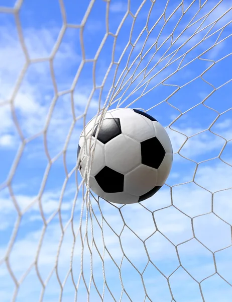 Футбольный мяч в сетке на голубом небе — стоковое фото