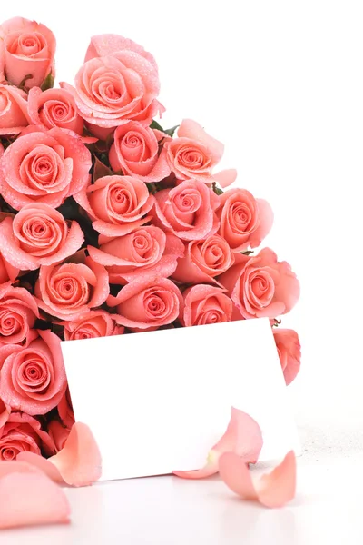 Rosas cor de rosa com papel de nota sobre fundo branco — Fotografia de Stock