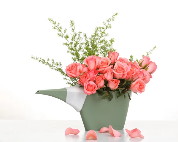 Розовые розы в пластиковой банке полива на столе — стоковое фото