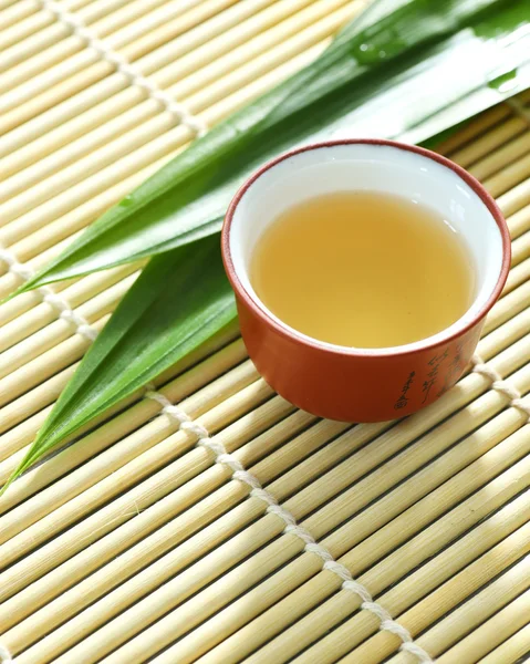 Tetera, taza de té y hojas de pandam en una estera de bambú — Foto de Stock