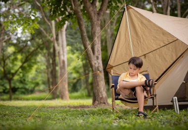 Şirin çocuk kamp sırasında çadırın önünde oturmuş kitap okuyor..