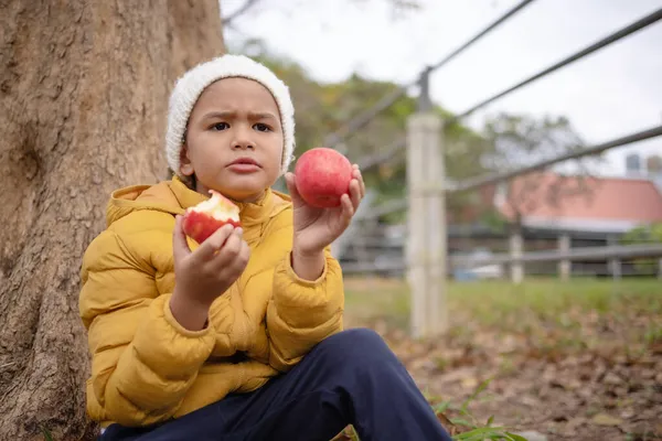 Ein Süßer Junge Wintermantel Zeigt Wie Apfel Isst — Stockfoto