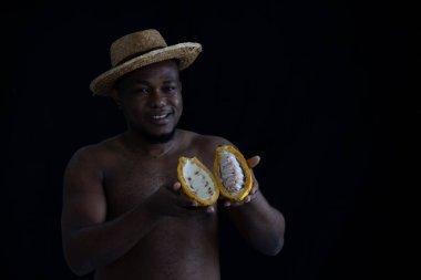 Siyah Afrikalı bir çiftçi, içinde taze tohumları göstermek için kakao meyvesi tutan hasır bir şapka takıyor. Kakao meyvesi Tayland 'da bulunan tropikal egzotik meyve tarlalarıdır..