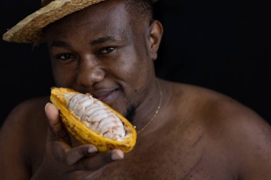 Siyah Afrikalı bir çiftçi, içinde taze tohumları göstermek için kakao meyvesi tutan hasır bir şapka takıyor. Kakao meyvesi Tayland 'da bulunan tropikal egzotik meyve tarlalarıdır..