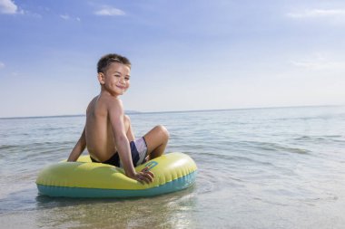 Kumsalda şamandıralarda yatan tatlı bir çocuk..