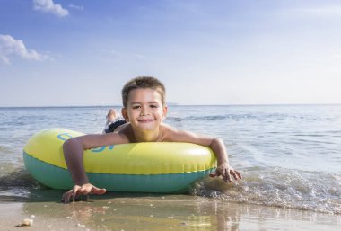 Kumsalda şamandıralarda yatan tatlı bir çocuk..
