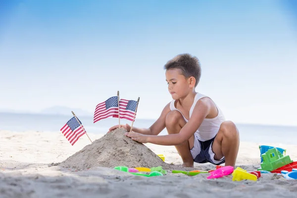Roztomilý Chlapec Hraje Hračku Pláži Hromadou Písku Americkou Vlajkou Vyšívané — Stock fotografie