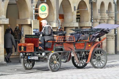 MUENSTER, GERMANY - 28 Şubat 2020: Tarihsel model elektrikli arabasıyla, sürücü şehir Muenster 'in eski kasabasında yürüyor ve soğutucunun önünde, Muenster gezisi için içkileri 28 Şubat 2020' de depoluyor