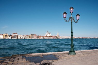 İtalya, Venedik, Guidecca gezinti güvertesindeki eski sokak lambası. Punta della Dogana ile Venedik silueti, Santa Maria della Salute kilisesi ve arka planda St Mark 's Campanile kulesi.