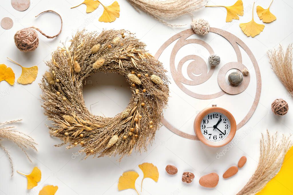 Autumn time background. Dried grass wreath, wood alarm clock, off white table with ginko leaves, stones and pampas grass. Fibonacci sequence circle, golden ratio. Fall background, top view, flat lay.