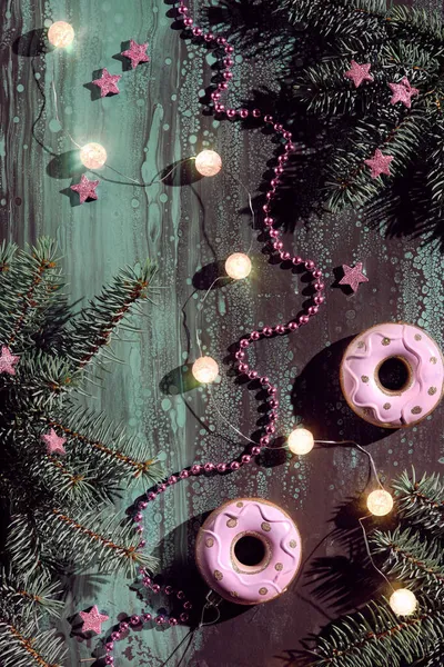 粉红甜甜圈和其他圣诞装饰在黑暗抽象的背景下 圣诞彩灯 球形花环 粉色的星星 闪亮的心形与冷杉枝条 — 图库照片