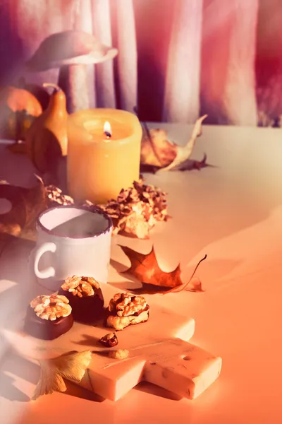 用核桃果仁装饰在大理石切板上的巧克力李子 糖果上的衣服 秋天布置与蜡烛 木菇和枯黄银杏叶 自然光 有很长的阴影 — 图库照片