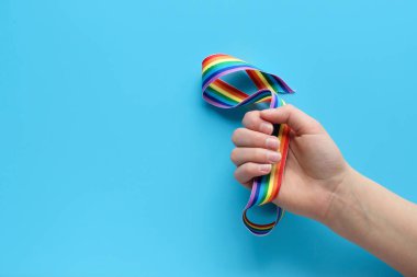 Çocuk elinde gökkuşağı kurdelesi. Mavi naneli kağıt arka planlar. Teşekkürler NHS çalışanları, doktorlar ve hemşireler düz konum, üst görünüm, minimum kompozisyon. Yaratıcı kavram arka planı.