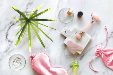 Uyku maskesi, nemlendirici, pembe Rosa Quarz yüz silindiri ve mermer kesim tahtasında gua sha taşı. Yüz masajı güzellik tedavisi. Silindirik sabitleme yaban bitki yaprağı.