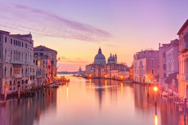 Şafak vakti romantik Venedik, gün doğumu. Santa Maria della Salute Basilica 'nın sakin denize yansıdığı Venedik' teki Büyük Kanal 'ın şehir manzarası. Durgun suya yansıyan sokak ışıkları.