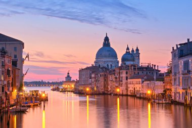 Şafak vakti romantik Venedik, gün doğumu. Santa Maria della Salute Basilica 'nın sakin denize yansıdığı Venedik' teki Büyük Kanal 'ın şehir manzarası. Durgun suya yansıyan sokak ışıkları.