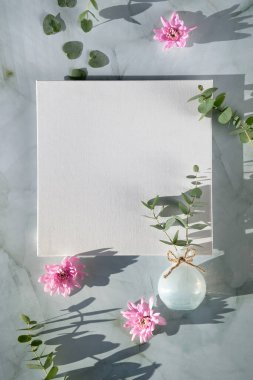 Boş kare tuval ve bahar dekorasyonlarıyla bahar zamanı maketi. Pembe chrysantemum çiçekleri, nane yeşili taşın üzerinde cam vazoda okaliptüs. Kopyalama alanı, harf, grafik tasarımı için yer.