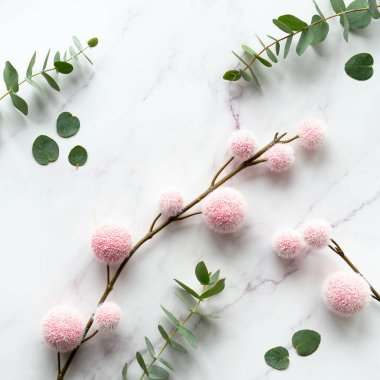 Taze okaliptüs yaprakları, pembe kabarık topları olan dallar. Panoramik afiş resmi. Kış yassı arka plan. Üst görünüm beyaz mermer masa üzerinde.