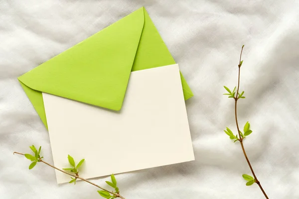 緑の封筒と白の紙のカード コピースペースを空白の春の背景 小枝に新春の葉 象牙の綿織物の背景 — ストック写真