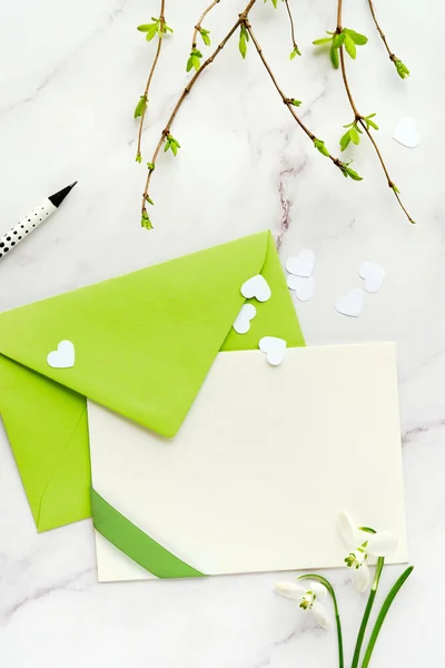 緑の色合いの春の背景 グリーティングカード コピースペースと紙の封筒 白い雪の花 白い背景のハートコンフェッティ — ストック写真