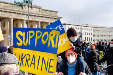 BERLİN, GERMANY - 27 Şubat 2022 Ukrayna metin desteğiyle pankart. Sarı mavi bayraklı ve posterli insanlar Brandenburg Kapısı önünde Ukrayna 'daki savaşı protesto ediyorlar..