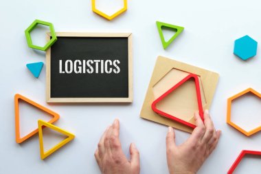 Tahtaya lojistik mesajı at. Gökkuşağı renklerinde iç içe geçmiş ahşap üçgenler, insan eli. Geometrik eğitim bulmacası. Montessori duyusal oyuncağı. Beyaz kağıt arkaplan üzerinde düz yatıyordu.