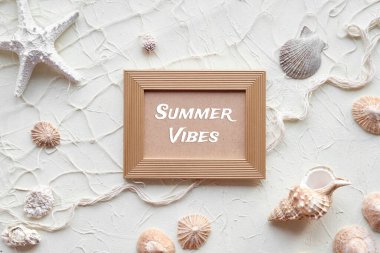 Summer Vibes 'a altın çerçeveyle mesaj at. Beyaz arka plan, deniz yıldızı, deniz kabuğu, deniz kabuğu, kolye. Krem bej kahverengi tek renkli arka planda balıkçı ağı. Yaz zamanı motivasyon arkaplanı.