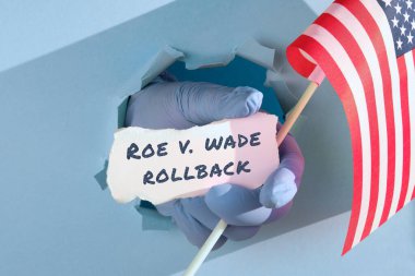 Roe, Wade Rollback 'e karşı Amerika Birleşik Devletleri bayrağı ve kağıt parçasında. Doktorlar ve doktorlar, ellerinde Amerikan bayrağı ve kağıt deliğinden geçen kağıt parçalarıyla eldiven tutuyorlar..