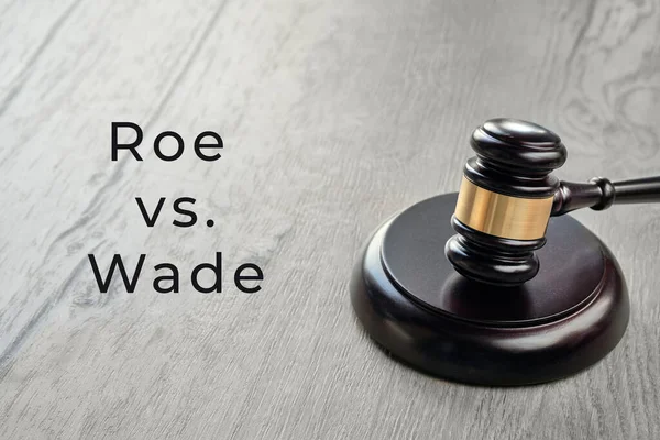 Roe versus Wade text. Law hammer with brass ring on wooden table.