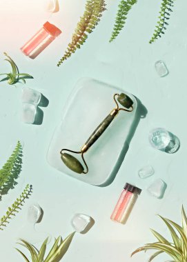 Yeşim taşı yuvarlayıcı ve buz küpleri ve nane yeşili arka planda egzotik palmiye eğreltiotu yaprakları ile kendi kendine nemlendirici. Yüz masajı konsepti, el yapımı kozmetik..