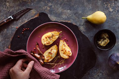 Baked pears with honey and red pepper. Flat lay, top view with fresh fig fruits and red towel on dark textured background.