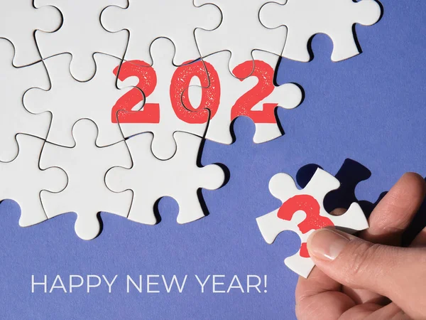 Jigsaw puzzle with numbers 2023, hand with missing piece, fingers add number 3 together with linked pieces. Lets meet together challenges of 2023, Happy New Year. Inspirational greeting card motivator