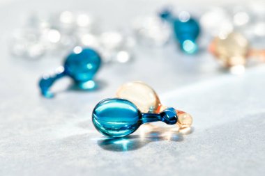 Sağlıklı cilt için serum kapsülleri. Kırışıklık önleyici cilt yenileme tedavisi. Güzellik ürünü sunumu, nane mavisi ve turuncu renkli..