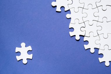 Yapboz parçalarının yarısı birleştirilmiş ve ayrılmış. Üst görünüm, tek renkli soyut mavi beyaz kağıdın üzerinde düz bir zemin. Kopyalama alanı, metin için yer.