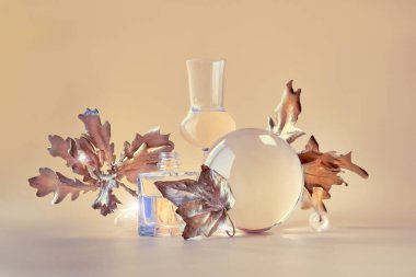 Biyofilik sonbahar geçmişi. Altın sarısı meşe yaprakları şeffaf cam kavanozlar ve küçük şişelerle bozulmuş. Tek renkli turuncu bej toprak renginde çiçek elementleri eşleşen arkaplanda yansımaları var..